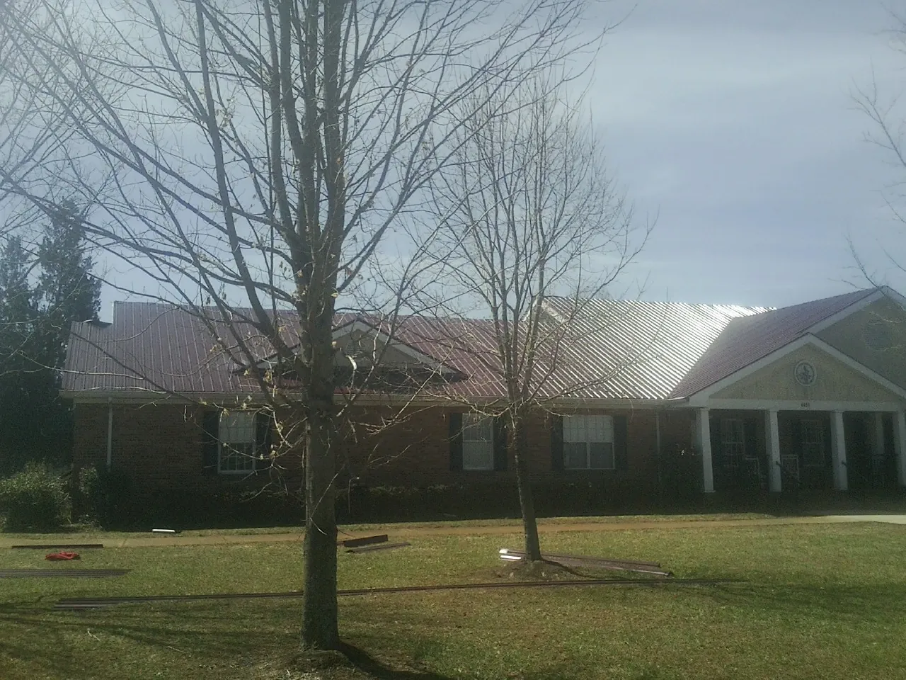 Red metal roof on a brick building seen from the front lawn in Howard