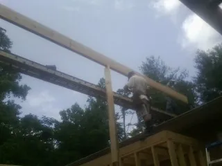Carpenter setting a ridge beam over a new addition frame — Ice Dam Removal by Roofing Brothers in Howard